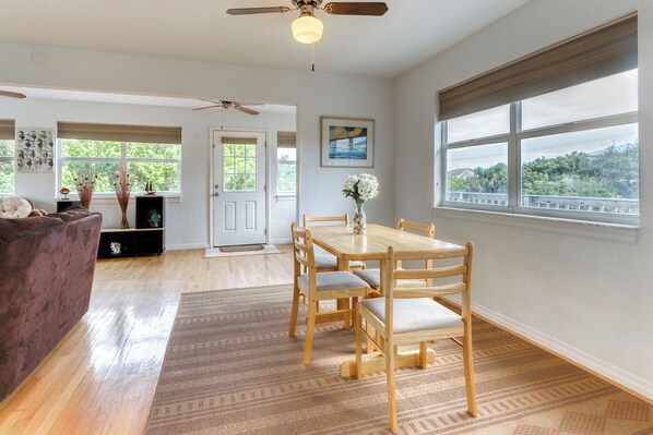 A spacious living room with a wooden dining table, chairs, and a ceiling fan.