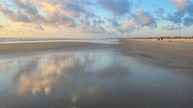 Een strand met een brede zandvlakte en een rustige zee.