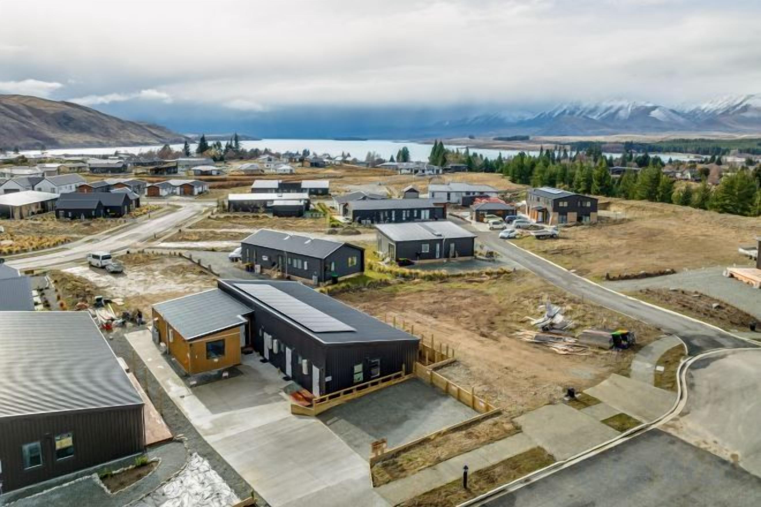 Vista aérea de una zona residencial con varias casas, carreteras y una masa de agua al fondo.