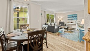 A spacious living room with a dining area, a sofa set, and a large window. - Colorful condo w/shared pool, free WiFi, central A/C - blocks from the beach (St. Augustine)