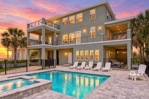 A multi-story building with a swimming pool and lounge chairs.