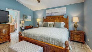 A bedroom with a large bed, wooden headboard, two bedside tables with lamps, a ceiling fan, and a television. - Dog-Friendly home with enclosed backyard, private hottub and sunroom (St. Augustine)