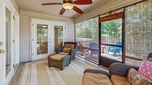 A covered porch with wicker furniture, a ceiling fan, and large windows. - Dog-Friendly home with enclosed backyard, private hottub and sunroom (St. Augustine)