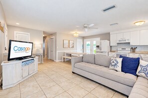 A modern living room with a flat-screen TV, a sofa, and a dining area.