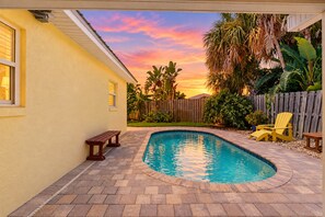 A backyard with a swimming pool, wooden deck, and a wooden fence.