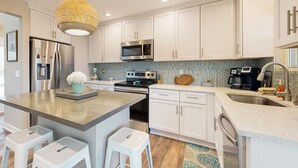 A modern kitchen with white cabinets, stainless steel appliances, and a central island with stools.
