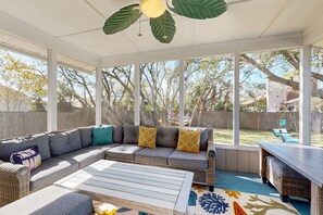Un patio cubierto con un sofá modular, una mesa de madera y un tapete estampado.
