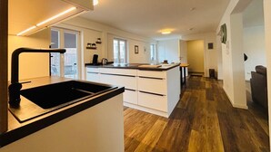 A modern kitchen with a central island, white cabinetry, and a view to the outside.