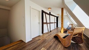 A modern interior with a high ceiling, wooden flooring, and a sloped roof allowing natural light.