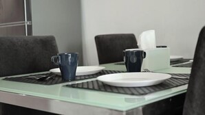 A dining table with two plates, two cups, and a tissue box. - Mansion One Suites by Simply Penang (George Town)