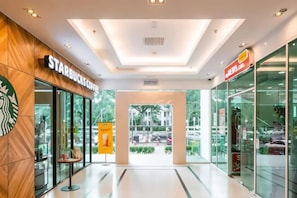 Interior moderno de un centro comercial con una cafetería Starbucks y una farmacia.