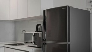 A modern kitchen with a stainless steel refrigerator, a microwave, and a sink. - Mansion One Suites by Simply Penang (George Town)