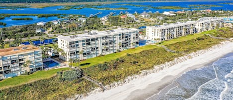 Ett hotell vid stranden med flera byggnader, en swimmingpool och en strand.
