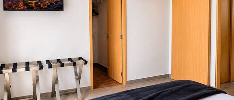 Habitación de hotel con cama, escritorio, equipo de aire acondicionado y un cuadro de paisaje urbano en la pared.