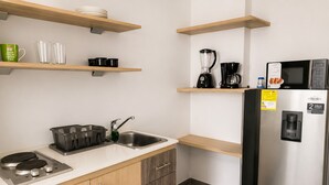 A modern kitchen with wooden cabinets, a stainless steel sink, a coffee maker, a blender, and a refrigerator. - Best bang for your buck in Laureles (Medellín)