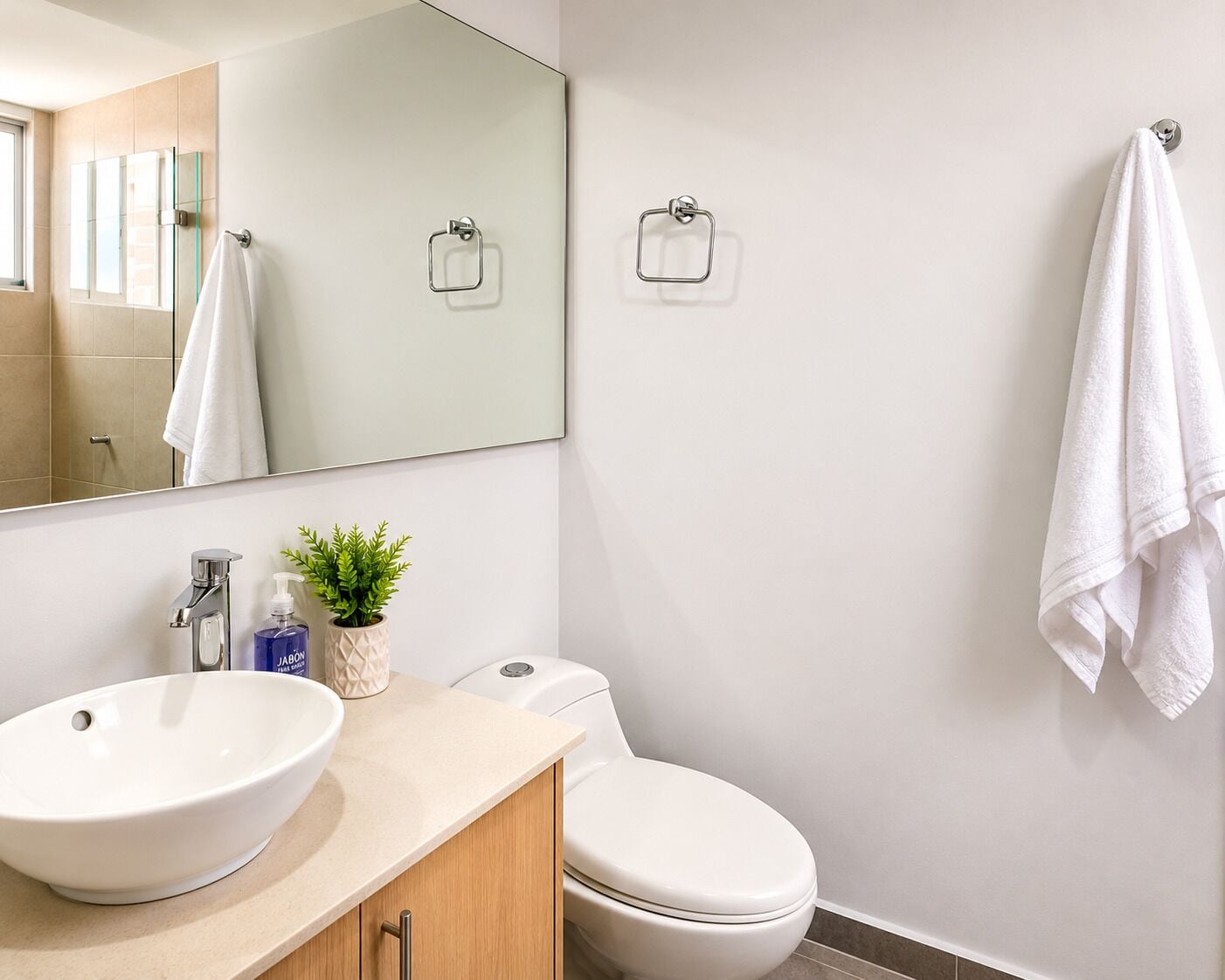 A bathroom with a large mirror, two sinks, a toilet, and a towel rack.