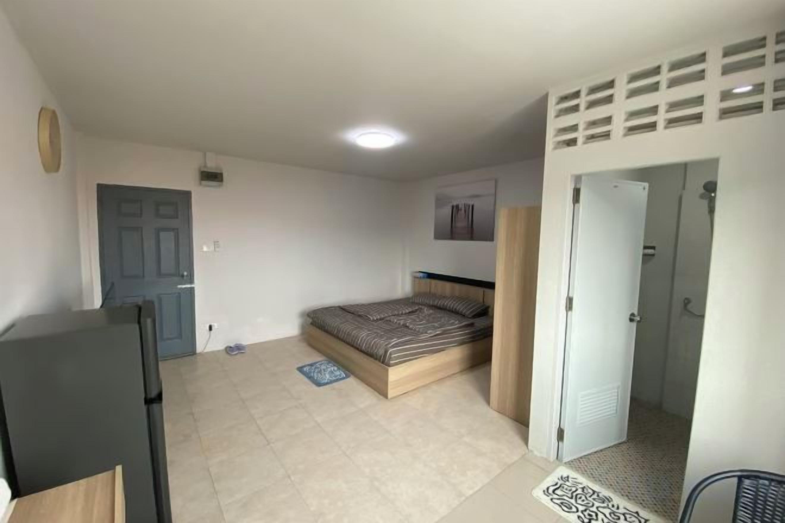 A bedroom with a bed, a wardrobe, a door, and a small table.