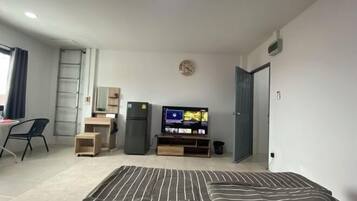 Ett litet rum med en säng, ett skrivbord, en tv och en garderob.