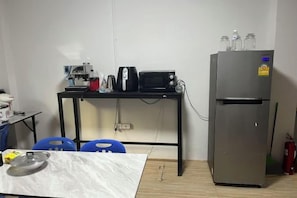 A compact kitchen with a refrigerator, microwave, and toaster on a black table. - 84 Bar & Guesthouse (Phuket)