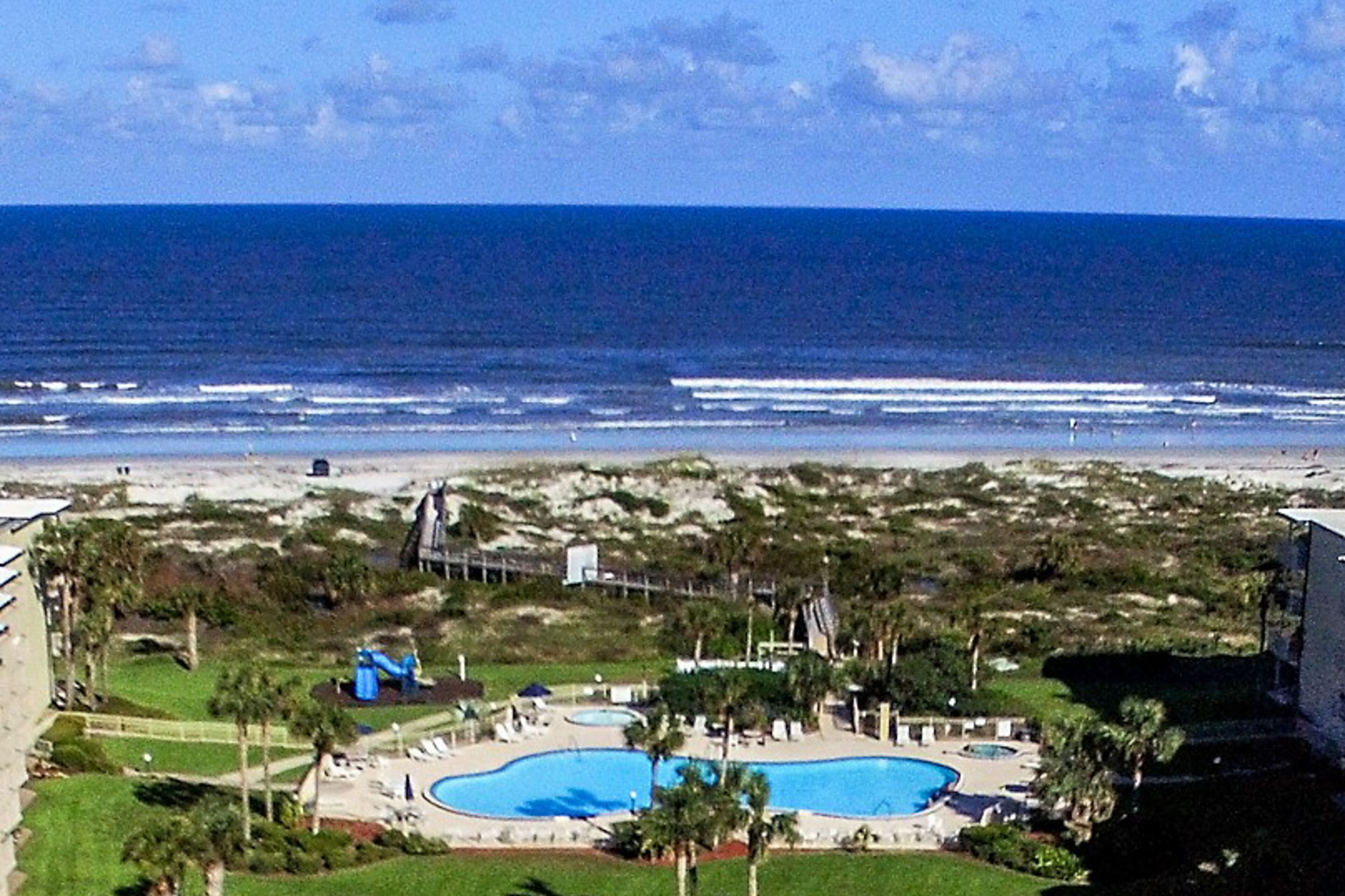 Een resort met een groot zwembad, toegang tot het strand en uitzicht op de oceaan.