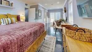 Une chambre avec un grand lit, un bureau et un panier en osier.