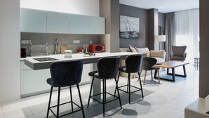 A modern kitchen with a central island, bar stools, a dining table, and a sofa in a contemporary living area. - Athens Soho Lofts - Evagelistrias Pedestrian (Athens)