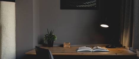 A desk with a plant, a book, and a lamp in a dimly lit room.