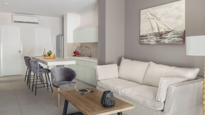 A modern living room with a white sofa, a wooden coffee table, and a painting of a sailboat on the wall. - Athens Soho Lofts - Evagelistrias Pedestrian (Athens)