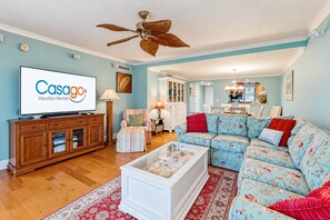A living room with a television, a ceiling fan, a sofa, and a coffee table.