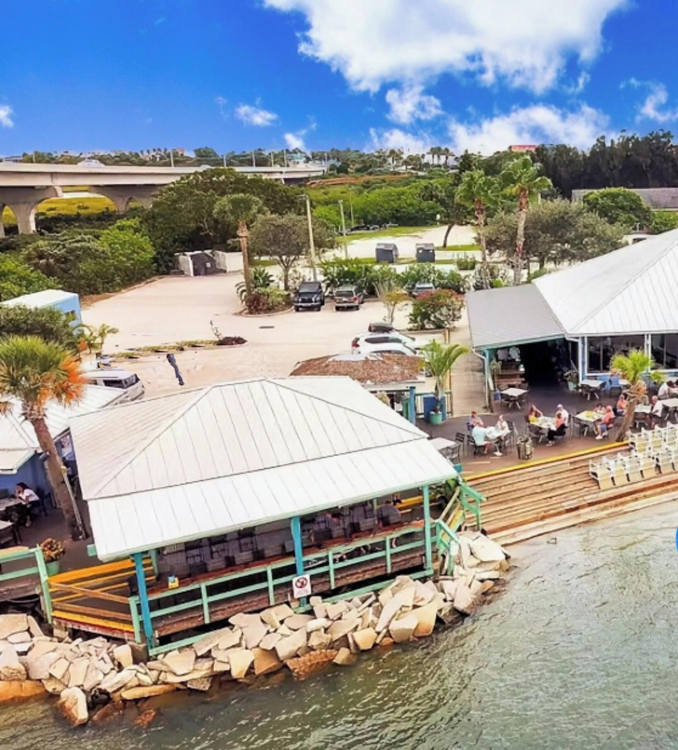 A beachfront property with a restaurant, outdoor seating, and a view of the water.
