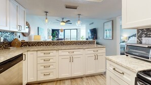 Een moderne keuken met witte kastjes, een granieten aanrechtblad en een inbouwvaatwasser.