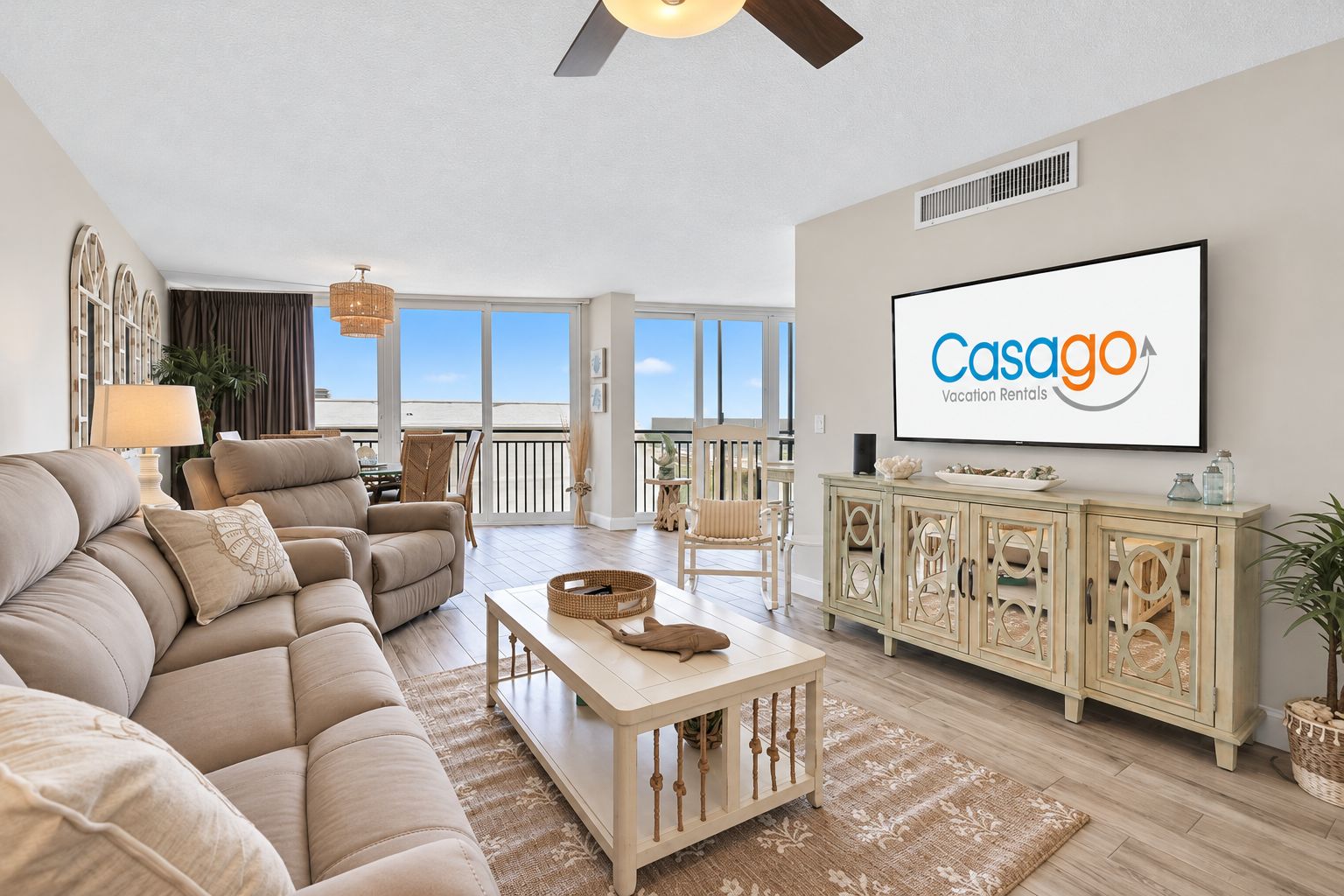 A spacious living room with a large sofa, a television, and a view of the ocean.
