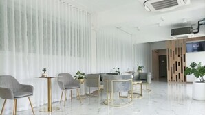Un moderno vestíbulo de hotel con piso de mármol, sillas tapizadas en gris, una mesa redonda y una recepción.