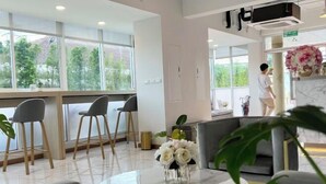 Un moderno vestíbulo de hotel con zona de bar, asientos y vistas a zonas verdes exteriores.
