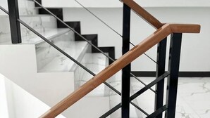 Una escalera moderna con barandillas de madera y soportes de metal negro.