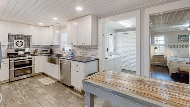 A modern kitchen with white cabinets, stainless steel appliances, and a wooden table. - Pet -Friendly Home Walking Distance to Down St Augustine (St. Augustine)