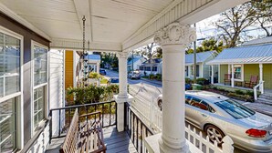 A porch with a white railing, a bench, and a view of a street with parked cars and houses. - Pet -Friendly Home Walking Distance to Down St Augustine (St. Augustine)