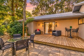 Une terrasse avec une table en verre, des chaises et une petite table ronde également accompagnée de chaises.