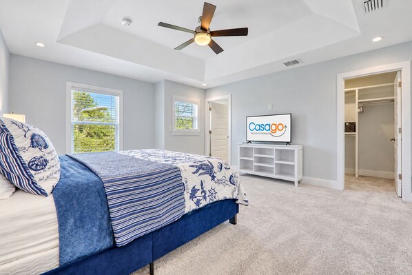 A bedroom with a bed, a ceiling fan, a TV, and a closet. - Spacious beach home - just a block from the ocean & the river (St. Augustine)