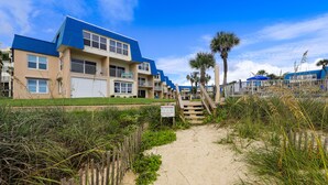 A beachfront property with a sandy pathway leading to a wooden staircase. - Island-themed living with furnished patio, shared pool & beach access (St. Augustine)