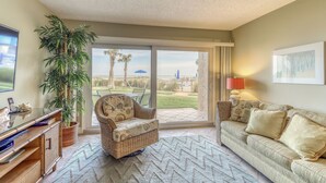 A living room with a sofa, armchair, and a large potted plant. - Island-themed living with furnished patio, shared pool & beach access (St. Augustine)