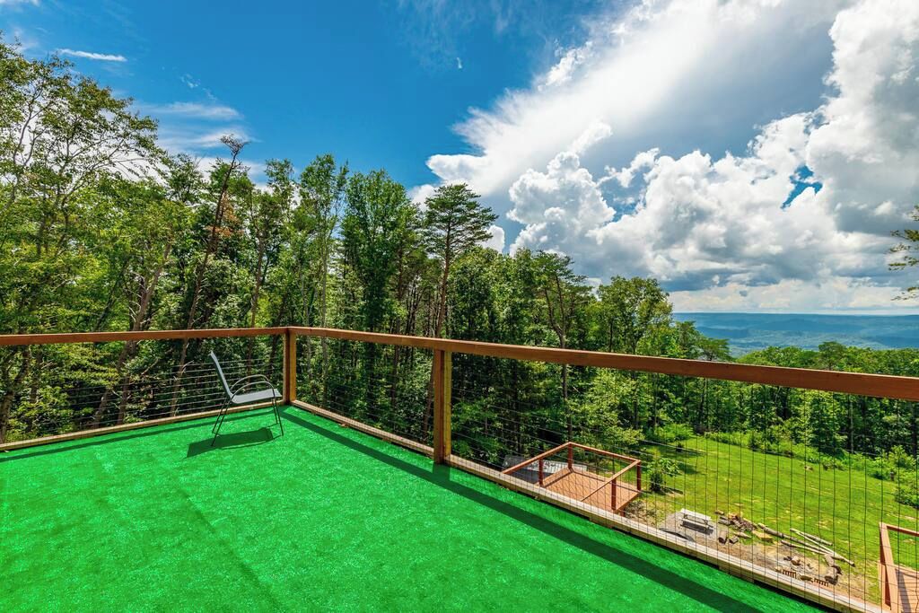 Een balkon met uitzicht op een bos en een heldere lucht.