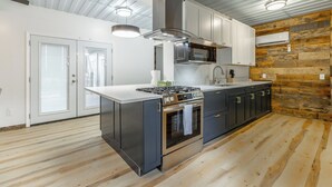 Eine moderne Küche mit einer zentralen Kochinsel, Edelstahlgeräten und einer Wandpaneele aus Holz.