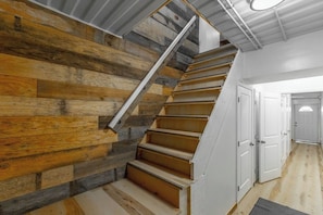 Un escalier avec des marches en bois, des murs blancs et un plafond en métal.