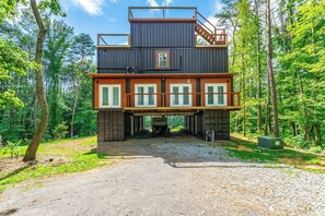 A cabin with a two-story structure, a covered entryway, and a gravel driveway. - Mountain Container Treehouse Lookout Mtn (Lookout Mountain)