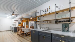 Une cuisine moderne avec des meubles de couleur sombre, un îlot central et une machine à café.