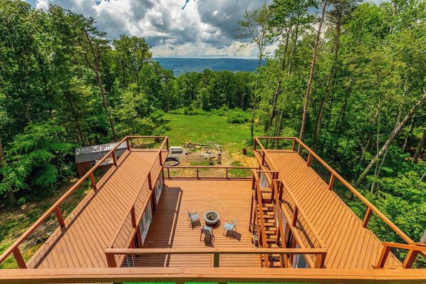 A wooden deck with outdoor seating and a view of a forested landscape.