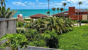 A coastal resort with a view of the ocean, palm trees, and a building with solar panels. - Hosts BR - Vista Mar no Cumbuco  (Caucaia)