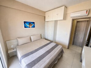 Une chambre à coucher avec un lit, une armoire, un miroir et un tableau accroché au mur.