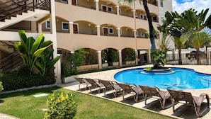 A multi-story hotel with a swimming pool, outdoor seating, and palm trees. - Hosts BR - Vista Mar no Cumbuco  (Caucaia)